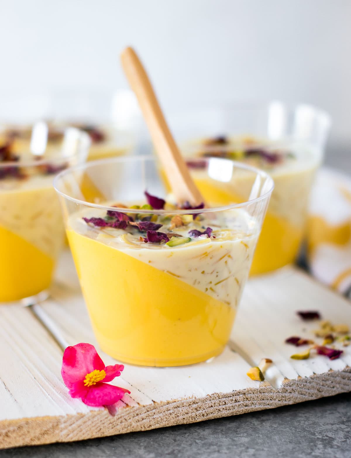Indian fusion dessert panna cotta and kheer layered in a glass and served with a spoon.