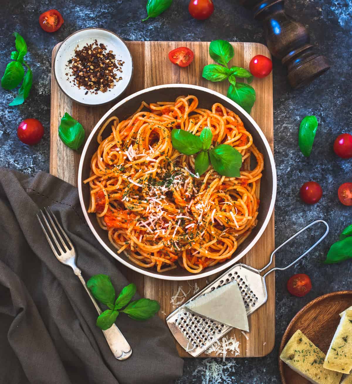 Pasta arrabiata served with cheese , red chili flakes and a fork