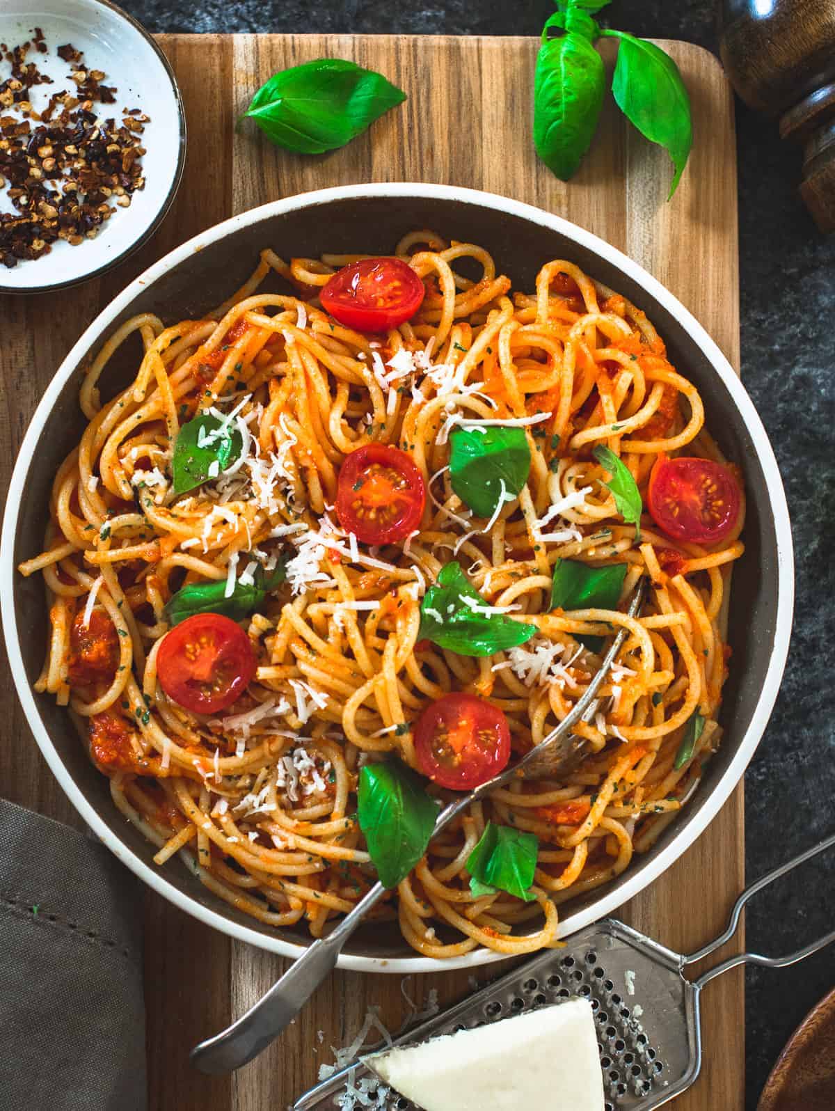 Spaghetti pasta in a brown dish with tomatoes