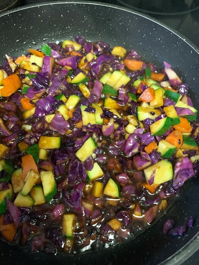 Adding vegetables and sauces to the pan.