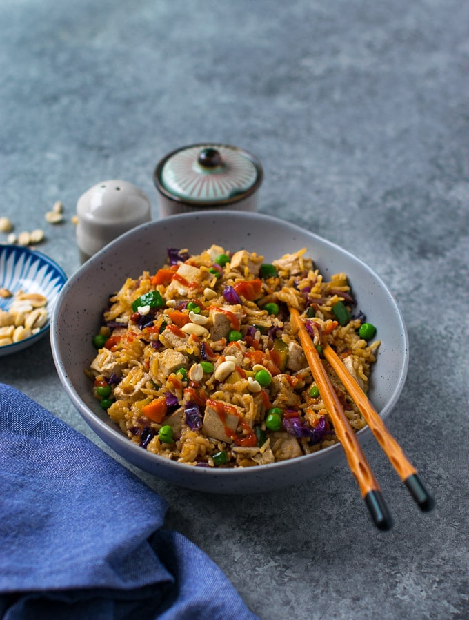 Vegetable tofu fried rice in a bowl with chopsticks.