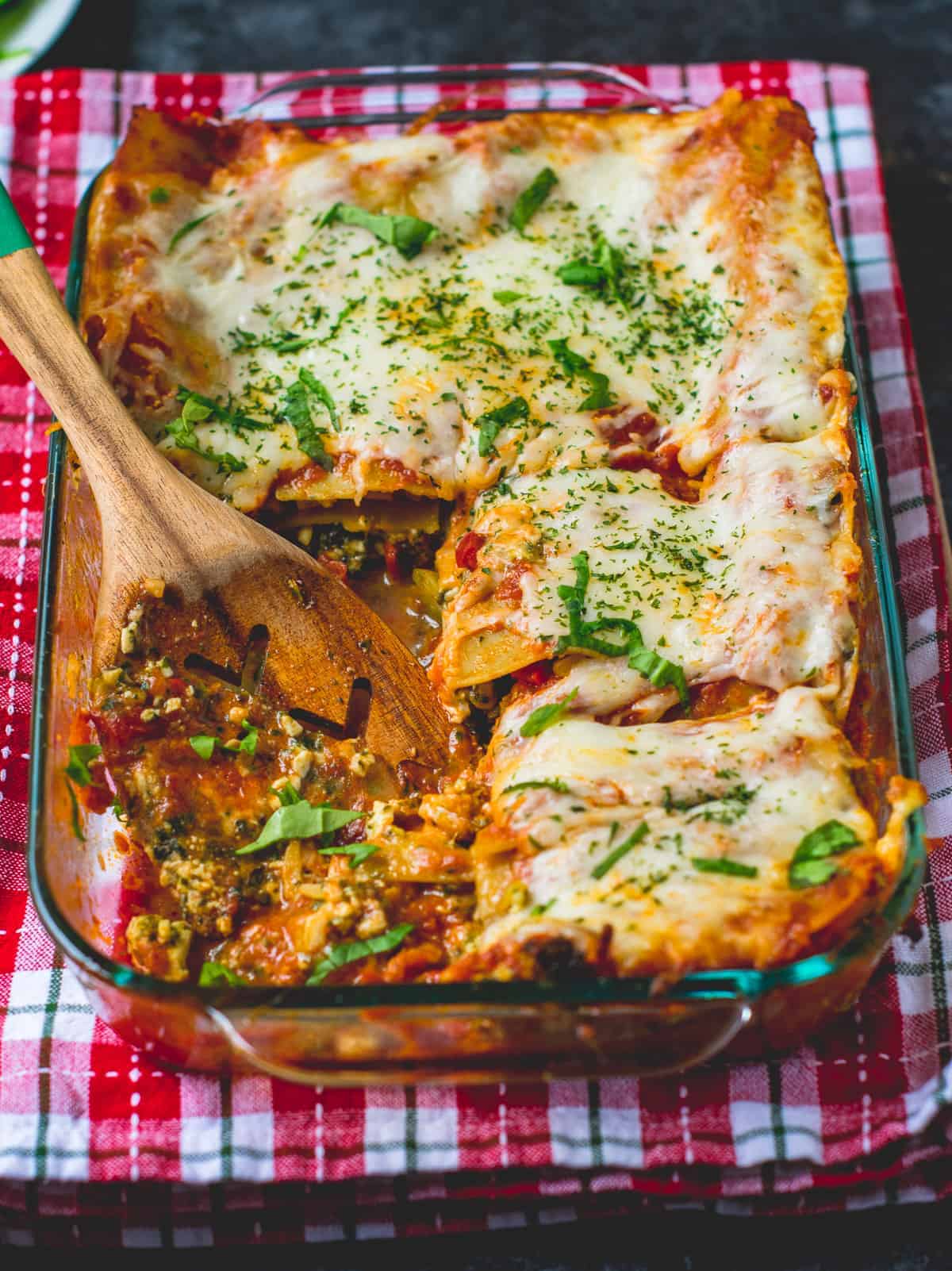 Veggie lasagna in a baking pan with a serving spoon