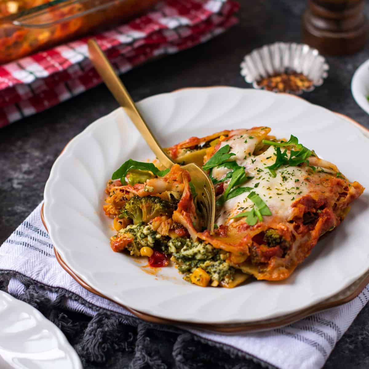 Veg lasagna served on a white plate with a fork