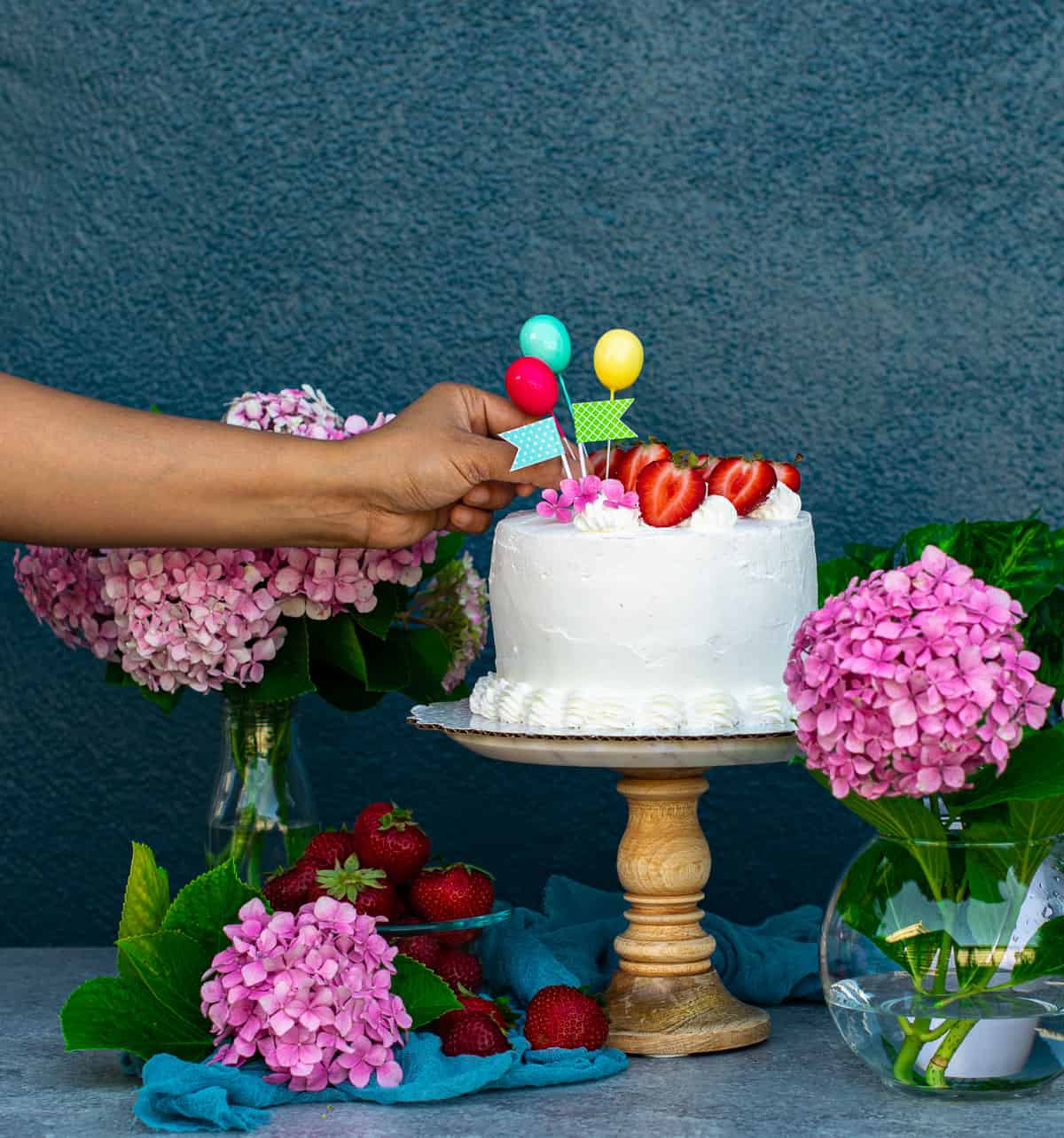 Putting decorations on Italian strawberry cream cake