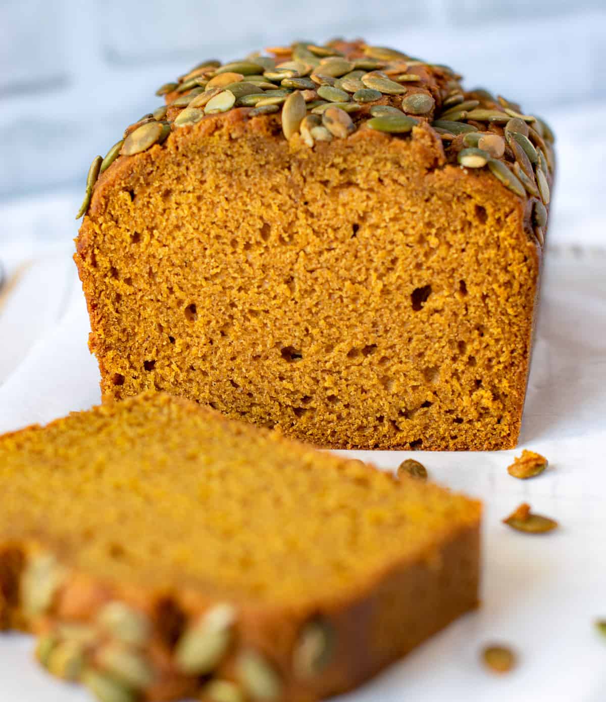 Pumpkin bread with seeds on the top and sliced on a board 