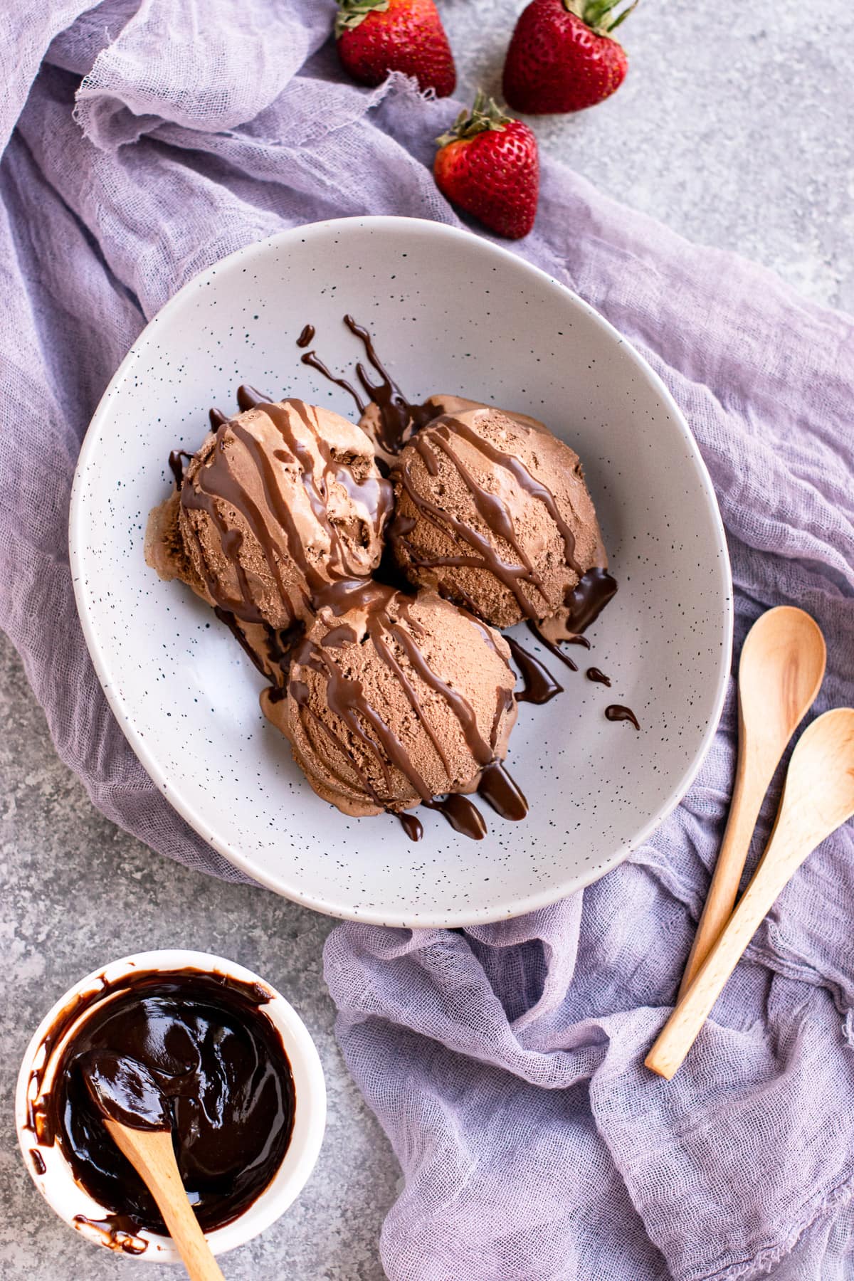 Homemade ice cream scoops in a bowl with chocolate sauce on the side