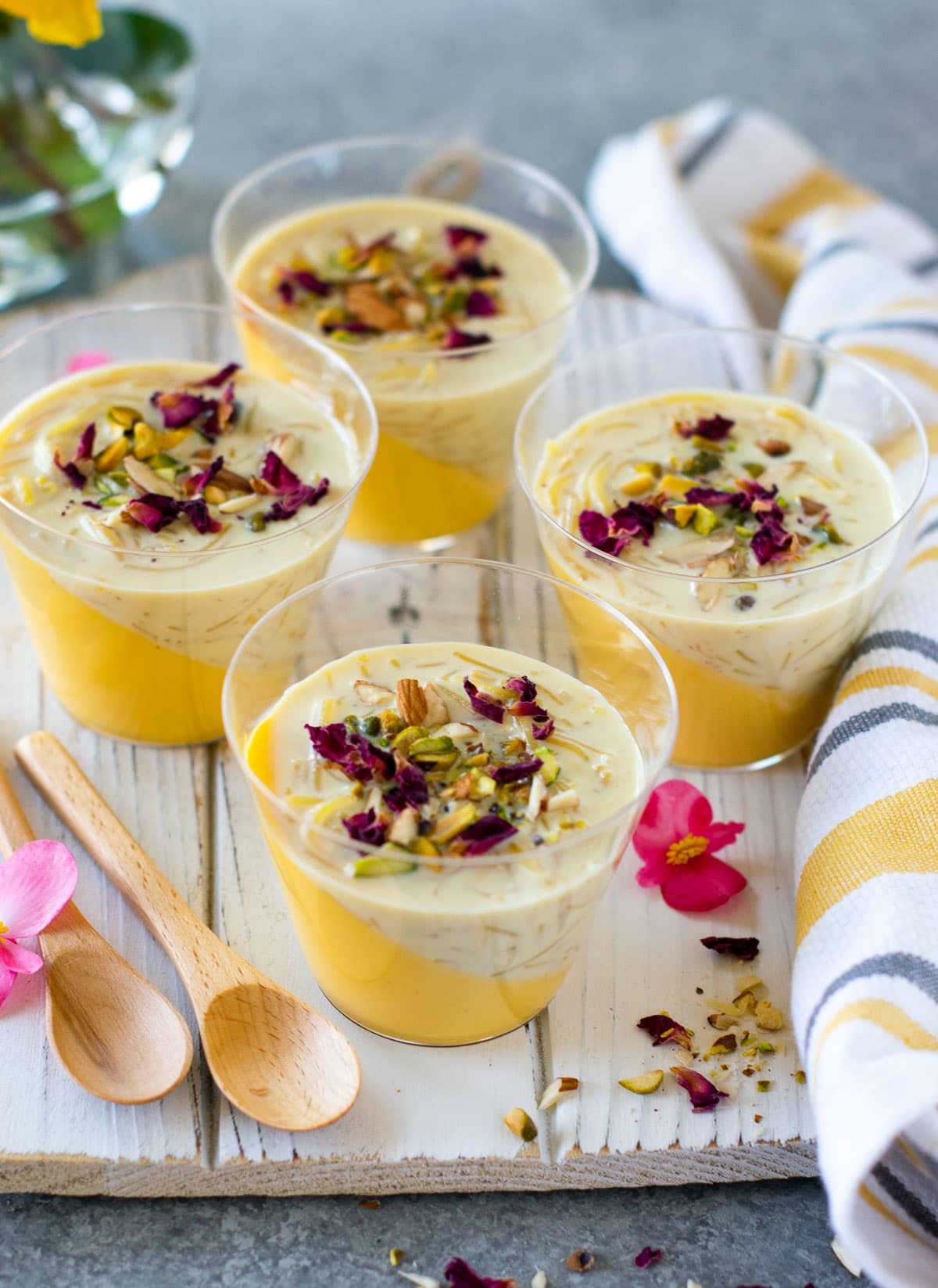 Clear disposable cups filled with mango panna cotta kheer dessert which is ready to be served. 