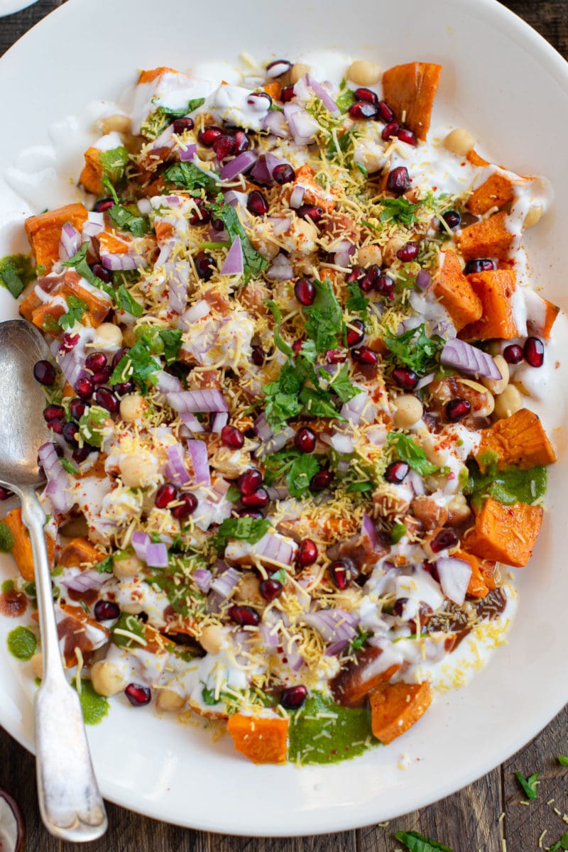Sweet Potato and chickpea chaat salad served in a white platter with yogurt on the top. 