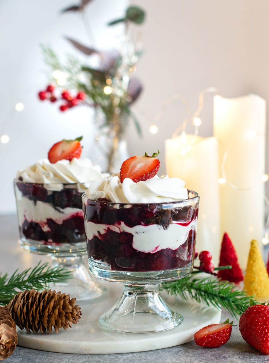 Berry Compote Chocolate Cake trifle filled in two glasses with candles lit on the side.