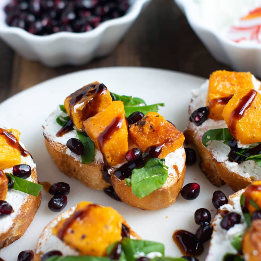 Butternut Squash Goat Cheese Crostini served on a white plate.