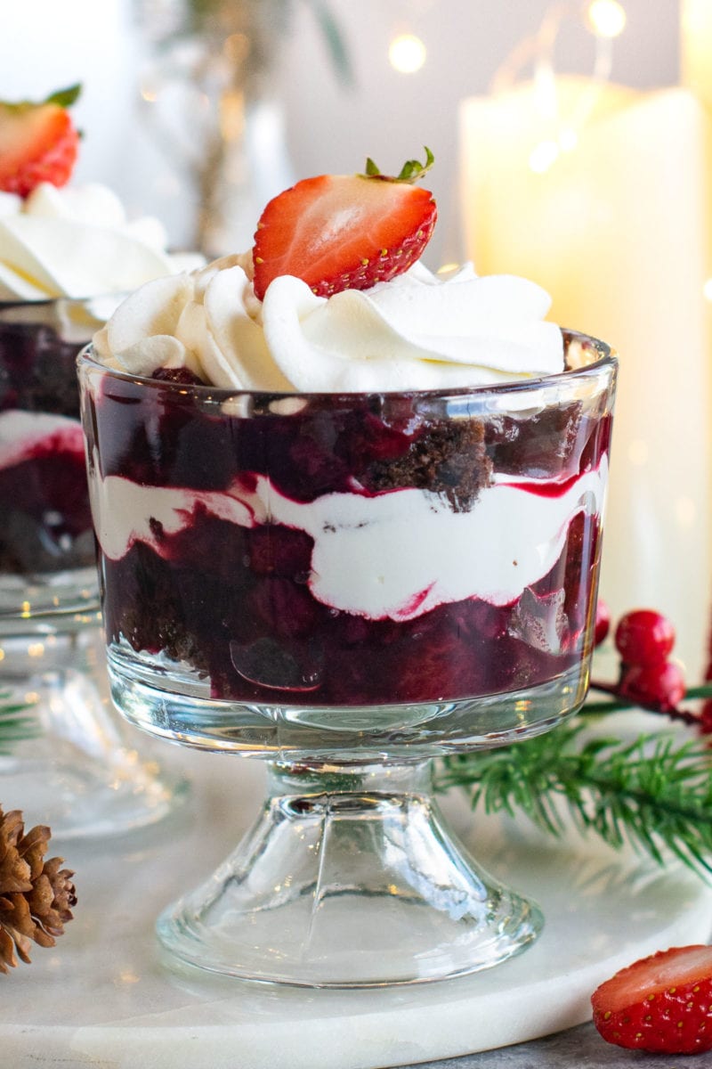 Layers of berry compote, chocolate cake and whipped cream in a trifle bowl. 