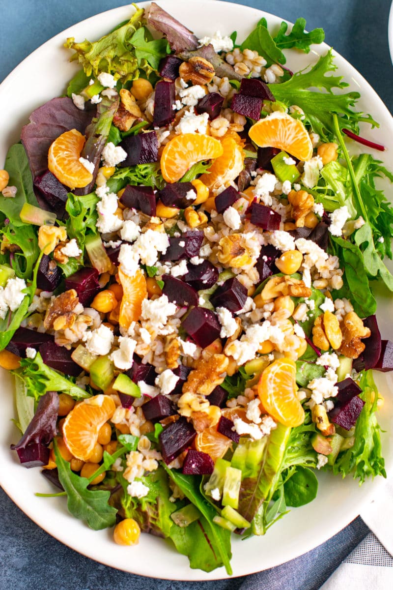 Beet barley salad with goat cheese, oranges and chickpea on a platter. 