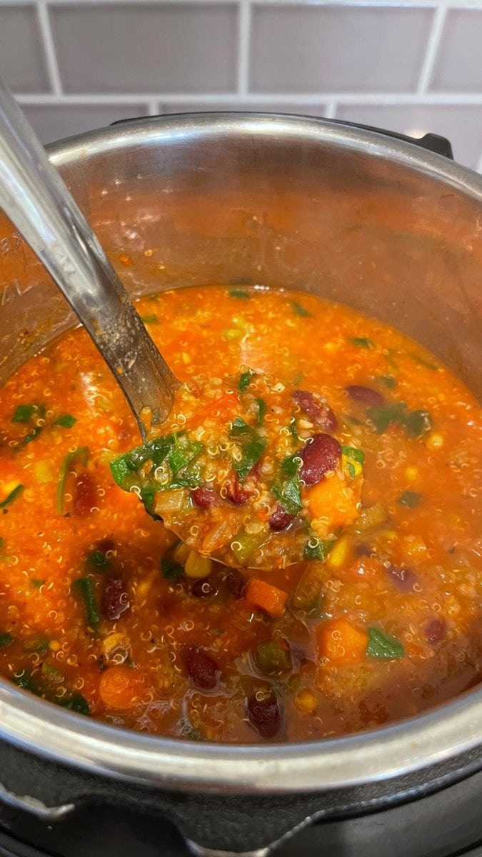 Vegan quinoa minestrone ready to be served with a ladle. 