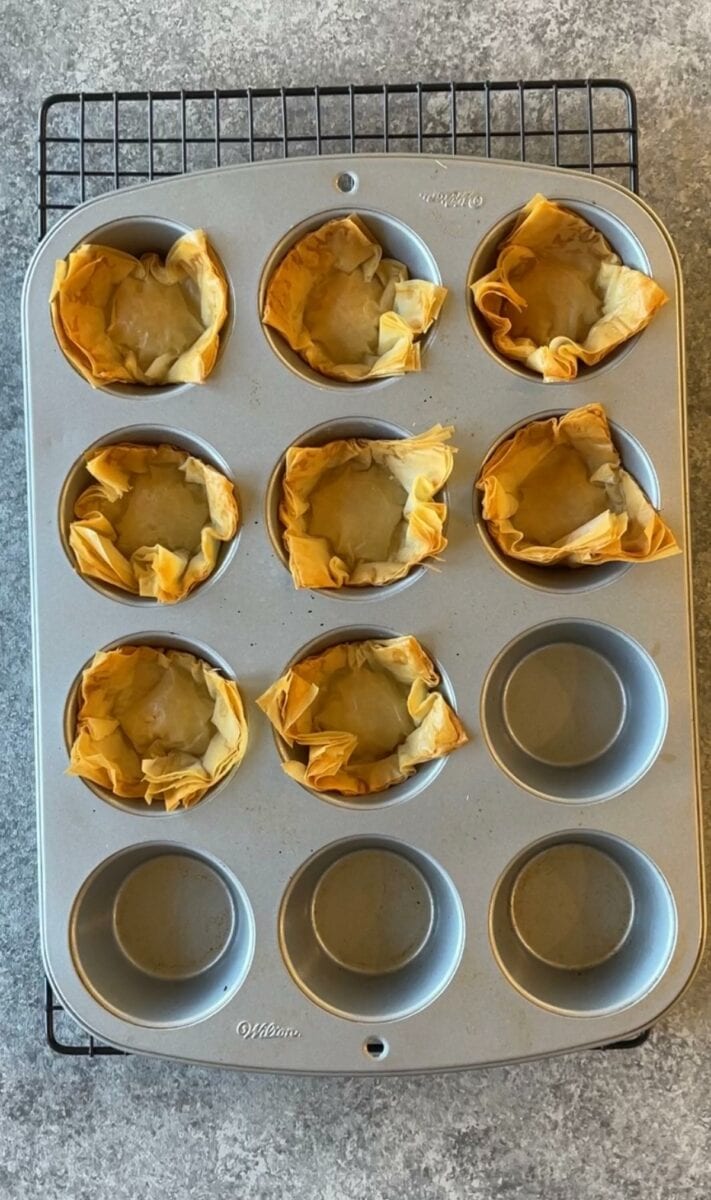 Baked phyllo cups are ready in a cupcake pan. 
