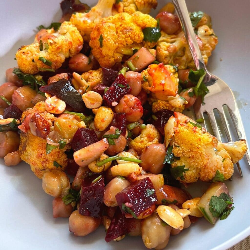 Roasted Beet Cauliflower Chickpea Salad served in a grey bowl with a fork.