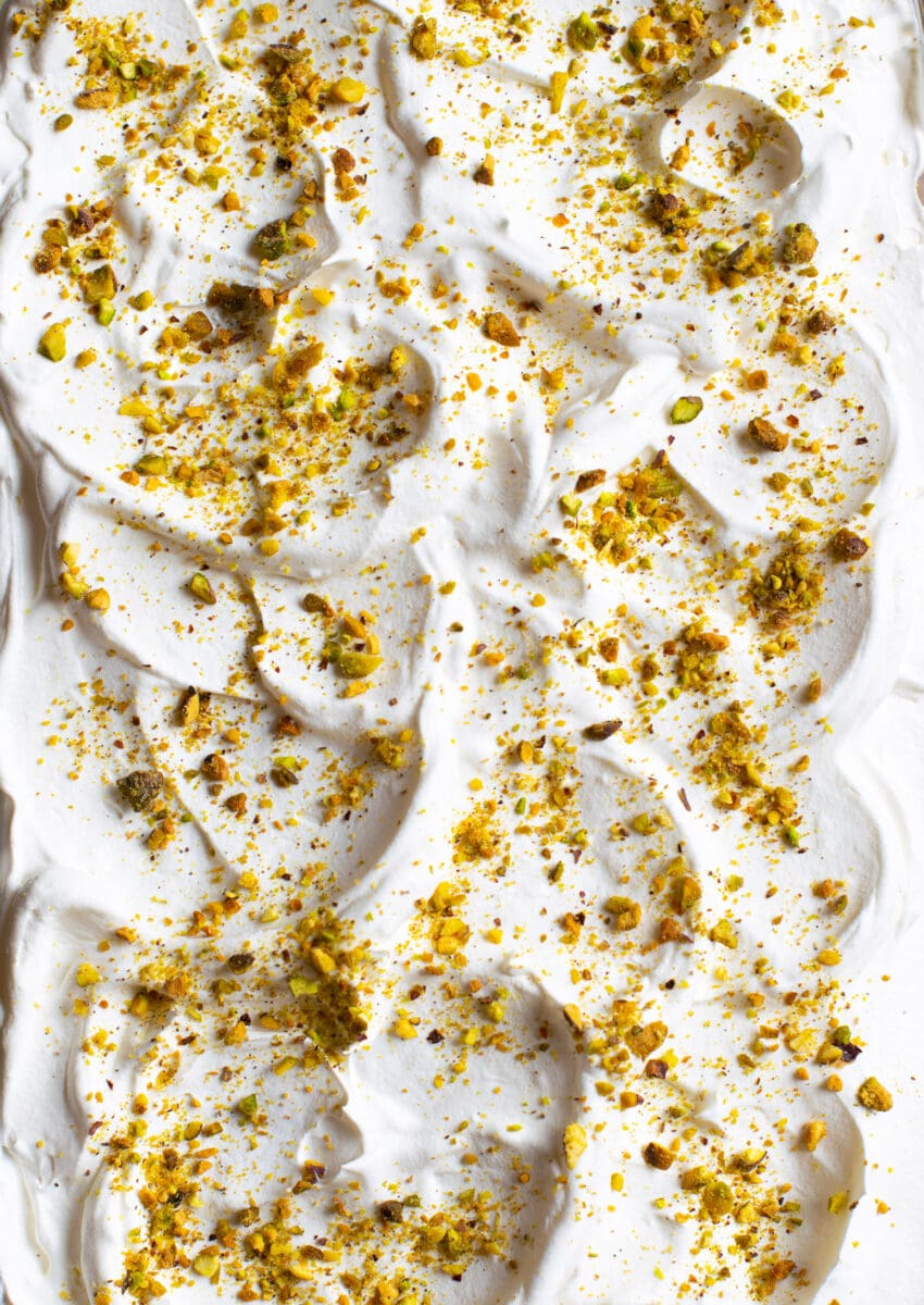 Rasmalai tres leches cake topped with whipped cream and pistachios. 