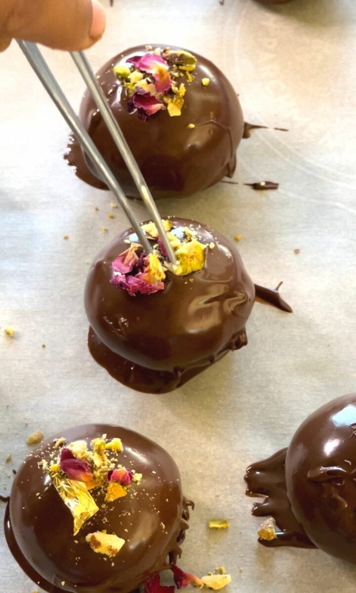 Adding nuts, dried rose petals and gold leaf garnish over the truffles. 