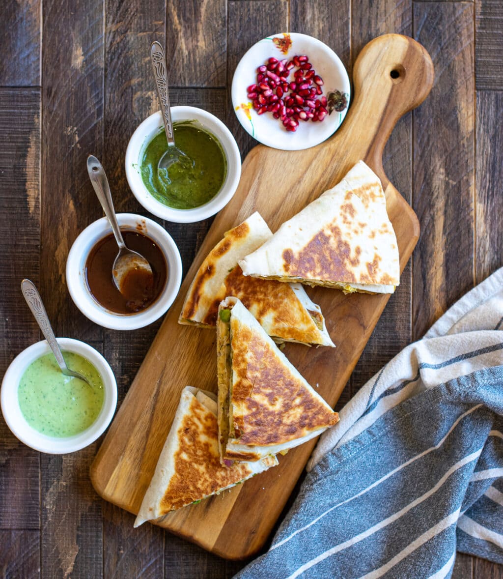 Samosa quesadillas served with pomegranate and dips on the side. 