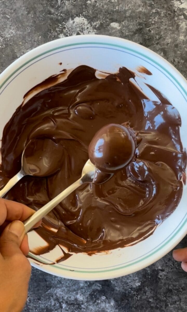 Covering the almond flour truffles with melted chocolate. 