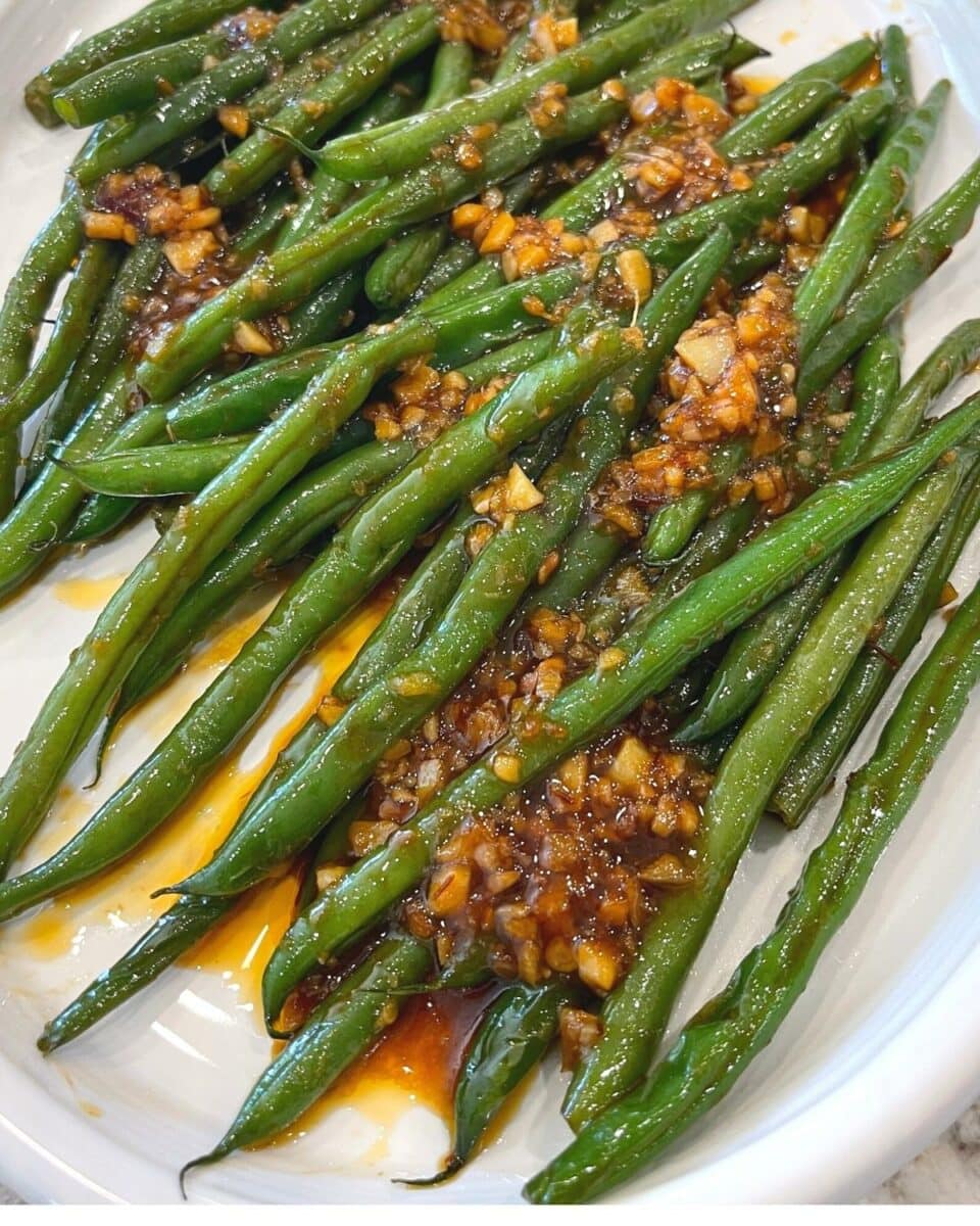 Chili garlic green beans served on a white plate. 