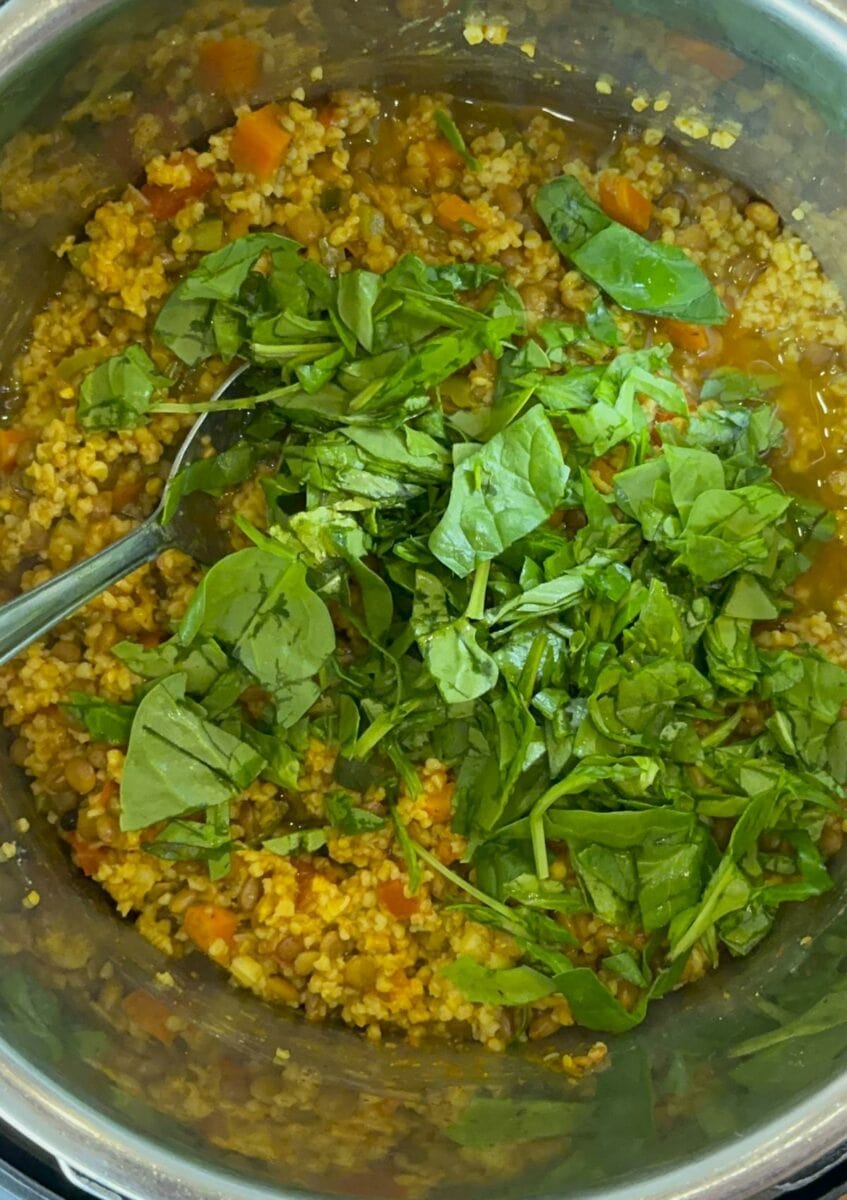 Adding spinach to the cooked khichdi. 