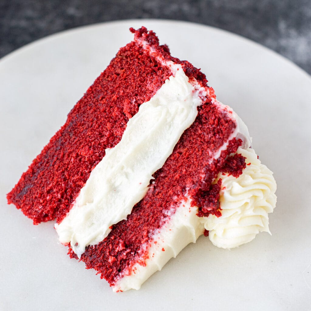 Slice of red velvet cake served on a white platter. 