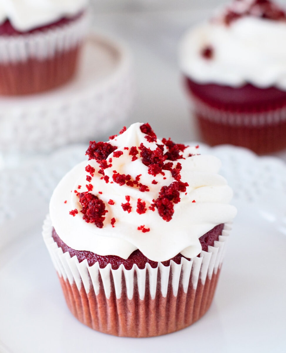 Red velvet cupcakes topped with cream cheese frosting and cake crumbs. 