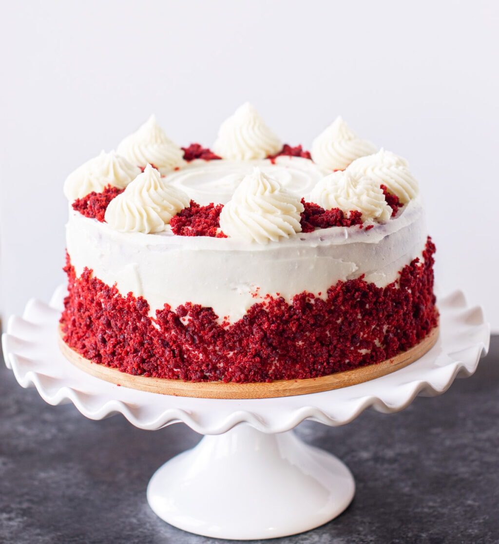 Eggless red velvet cake on a white cake stand. 